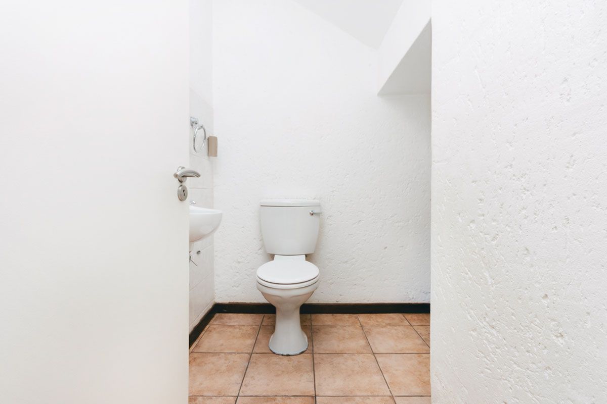 A compact guest bathroom featuring a white toilet and a small wall-mounted basin with tiled flooring.