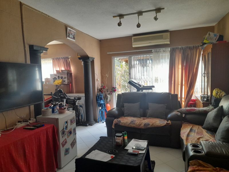 A living room featuring tiled flooring, decorative columns, an archway, and an air conditioning unit, with direct access to the outdoor area via sliding doors.
