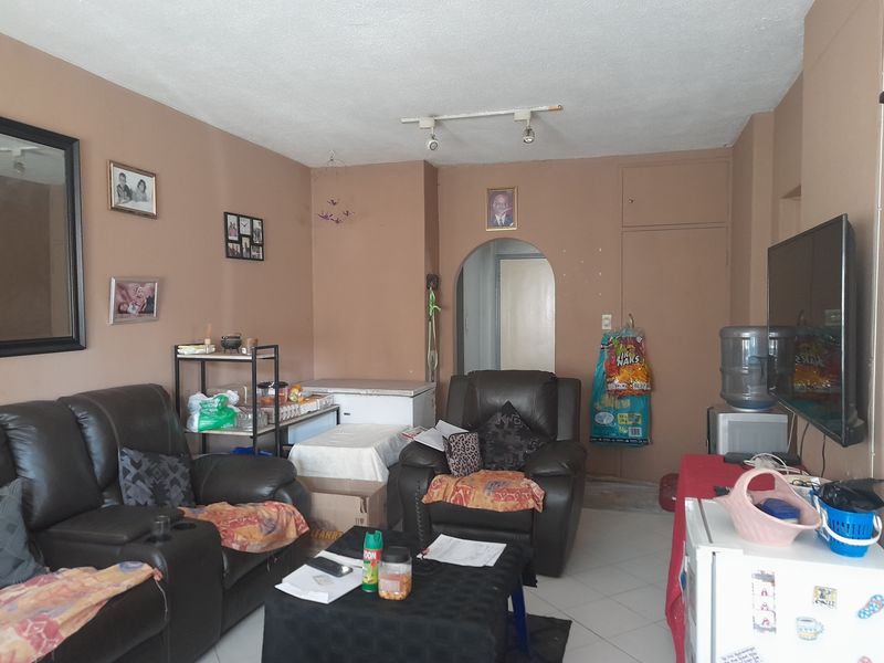 A living room featuring tiled flooring, an arched doorway, and built-in storage, currently used as a multi-functional living space.