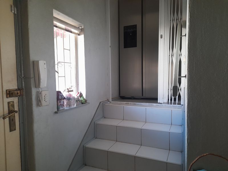 Entrance area featuring a tiled staircase, security gate, and intercom system, providing access to the upper level of the property.