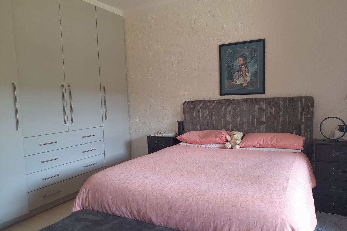 A well-maintained bedroom featuring neutral-toned built-in cupboards and a clean, functional layout.