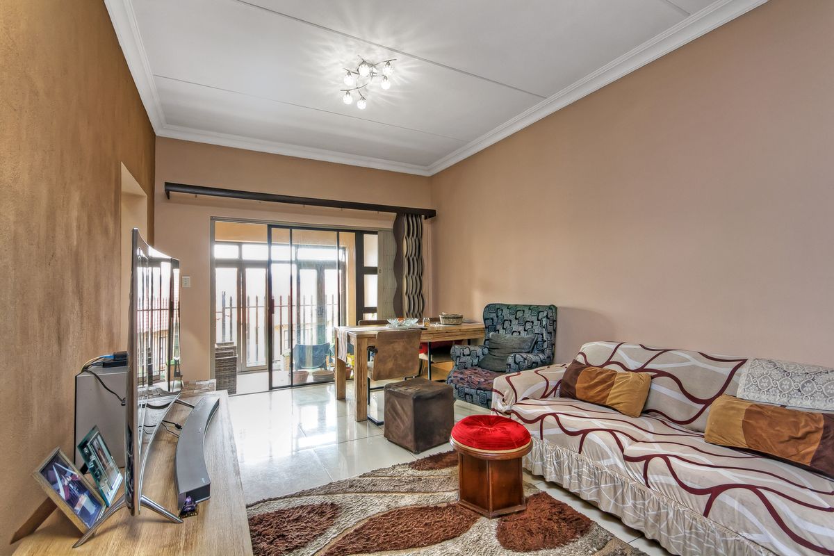 A living room featuring tiled flooring, a sliding glass door leading to an outdoor area, and decorative ceiling cornicing.