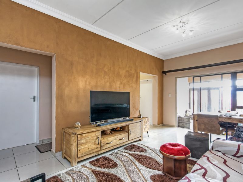 A living room featuring tiled flooring, textured accent wall, and sliding glass doors leading to an outdoor area.