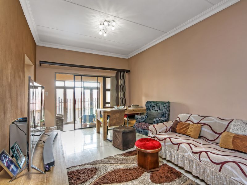 A living room featuring tiled flooring, a sliding glass door leading to an outdoor area, and decorative ceiling cornicing.