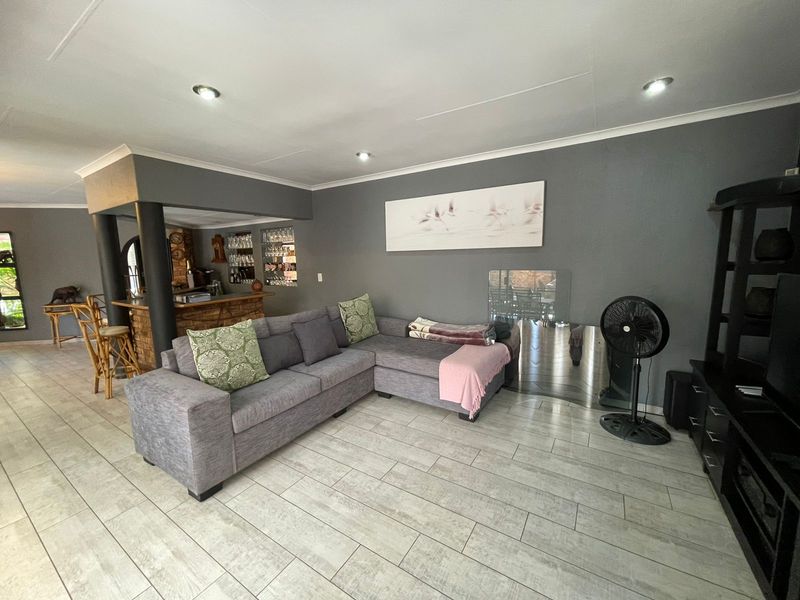 Open plan living area featuring tiled flooring, recessed downlighting, and an integrated bar area with a brick facade.