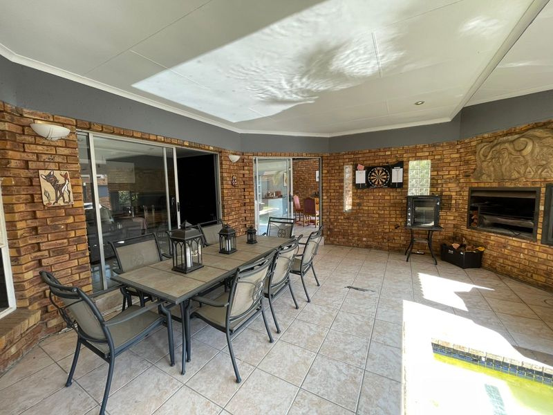 Covered patio area featuring exposed brick walls, a built-in fireplace, and tiled flooring, providing a functional space for outdoor entertaining.