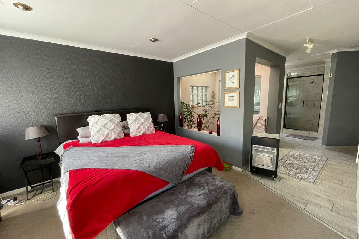 Spacious bedroom featuring an open-plan layout with an integrated en-suite bathroom, dark accent wall, and tiled flooring transition.