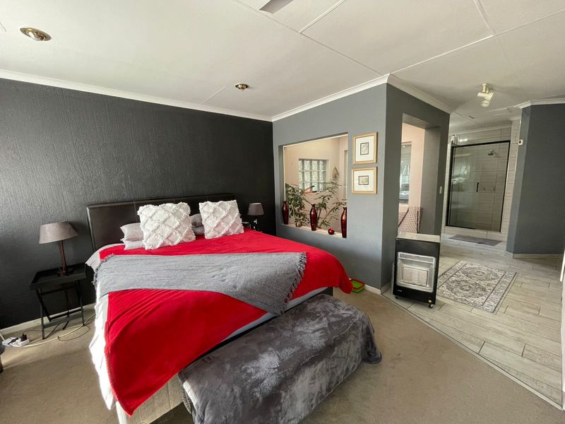 Spacious bedroom featuring an open-plan layout with an integrated en-suite bathroom, dark accent wall, and tiled flooring transition.