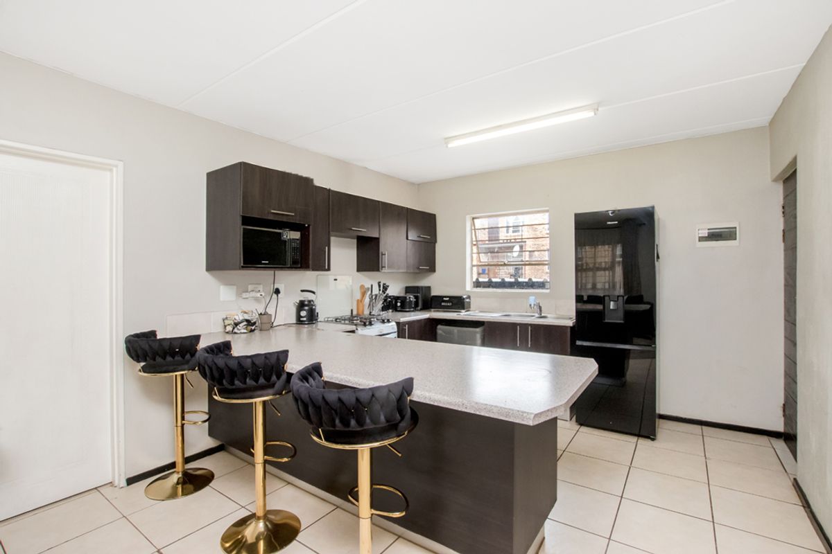 A functional kitchen featuring dark cabinetry, a breakfast bar, tiled flooring, and a built-in stove with an extractor fan.
