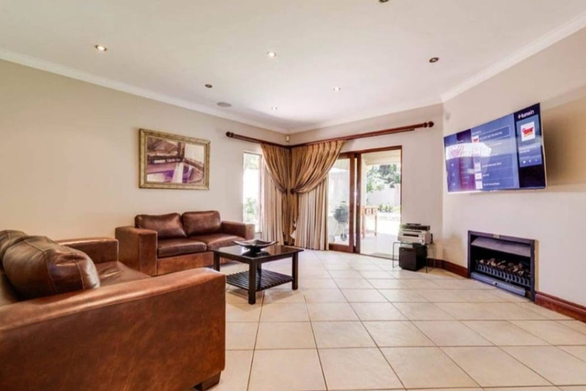 Spacious living room featuring tiled flooring, recessed downlights, and a built-in fireplace, with direct access to the outdoor patio area.