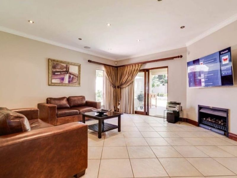 Spacious living room featuring tiled flooring, recessed downlights, and a built-in fireplace, with direct access to the outdoor patio area.