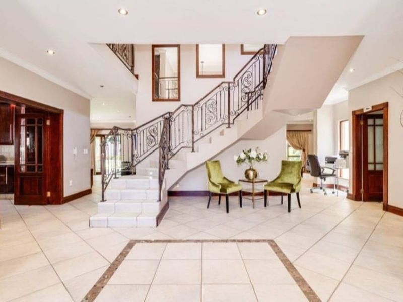 Spacious entrance hall featuring tiled flooring, recessed lighting, and an elegant staircase with a decorative wrought iron balustrade.