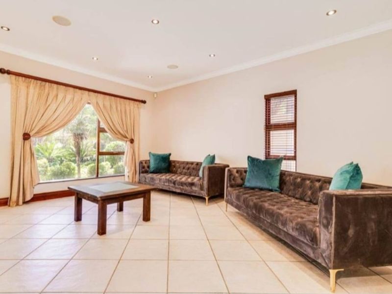 A spacious living room featuring neutral tiled flooring, recessed downlighting, and large windows that provide ample natural light.