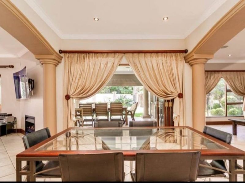Spacious open-plan living and dining area featuring decorative columns, tiled flooring, and large sliding doors that provide seamless access to the outdoor patio.