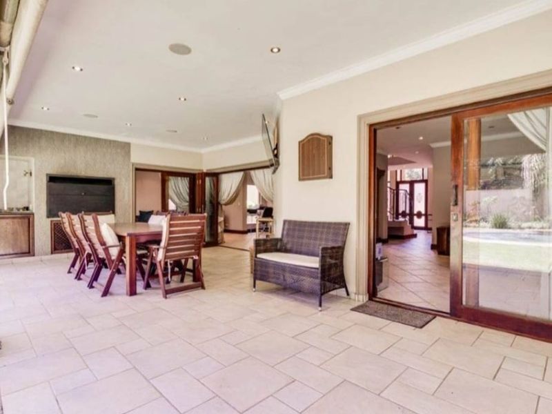Spacious covered patio featuring tiled flooring, recessed lighting, and a built-in braai, providing seamless indoor-outdoor flow through large sliding glass doors.