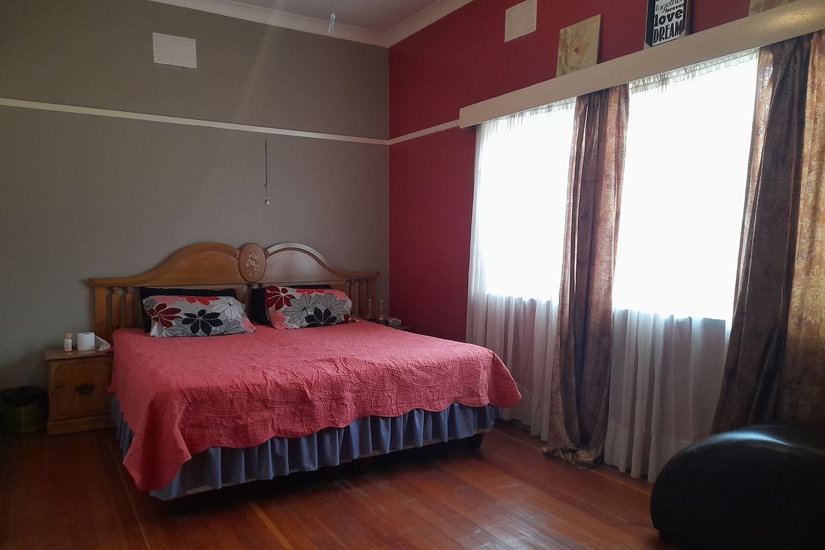 A spacious bedroom featuring original hardwood flooring, coved ceilings, and a classic picture rail, offering a solid foundation for modern interior updates.