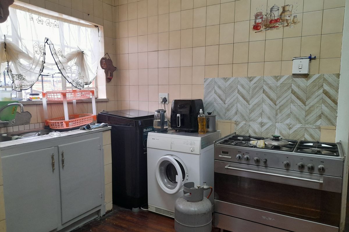 A functional kitchen featuring built-in cabinetry, a stainless steel gas stove, and tiled splashbacks, offering a practical layout for daily cooking and utility needs.