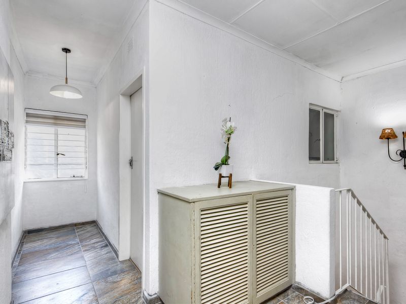 A bright hallway featuring tiled flooring, a staircase with a metal balustrade, and built-in storage cabinetry.