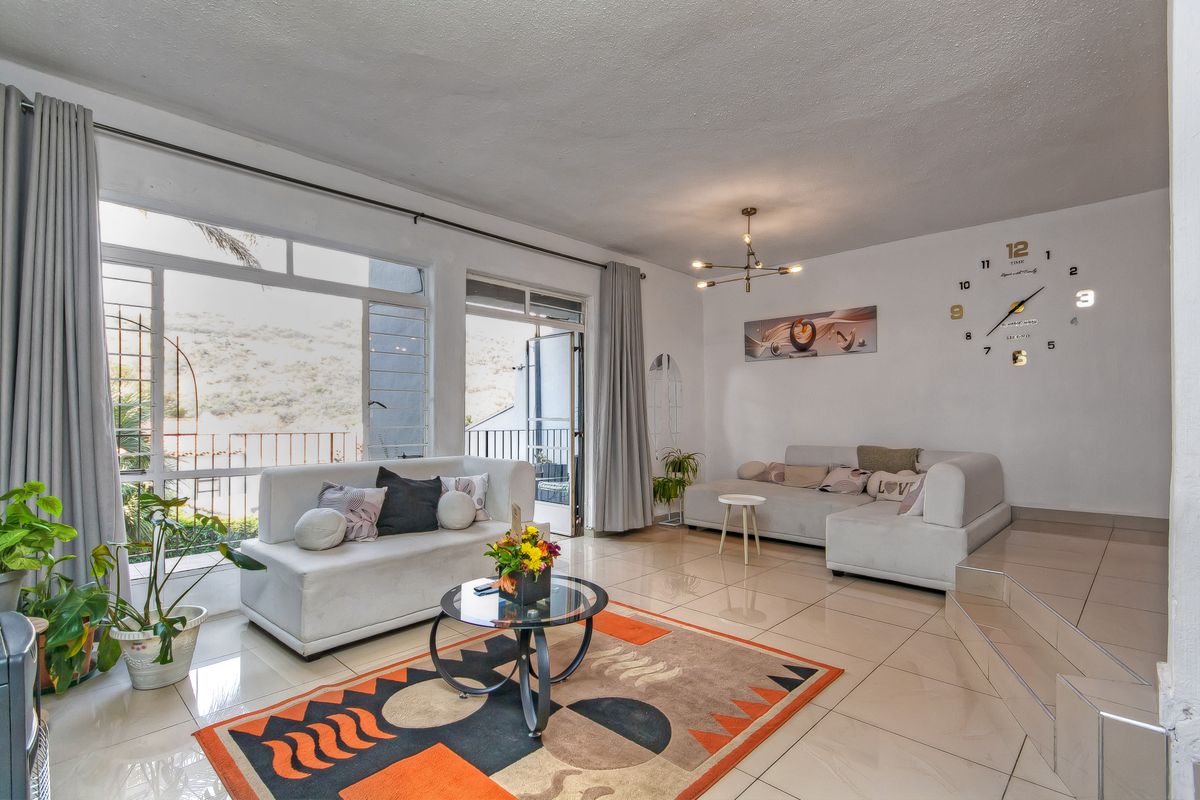 Spacious living room featuring large windows, tiled flooring, and direct access to an outdoor balcony area.