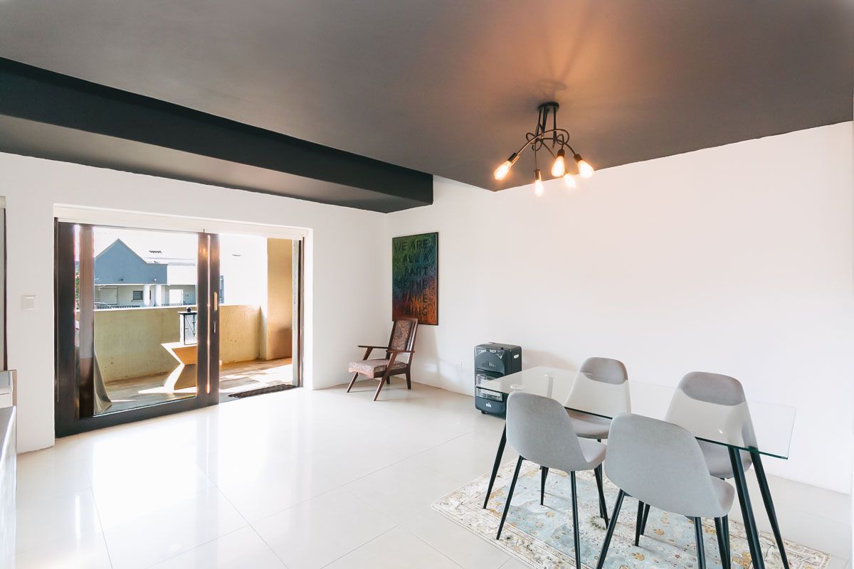 Bright living area featuring large sliding glass doors leading to a balcony, neutral tiled flooring, and a contemporary chandelier.