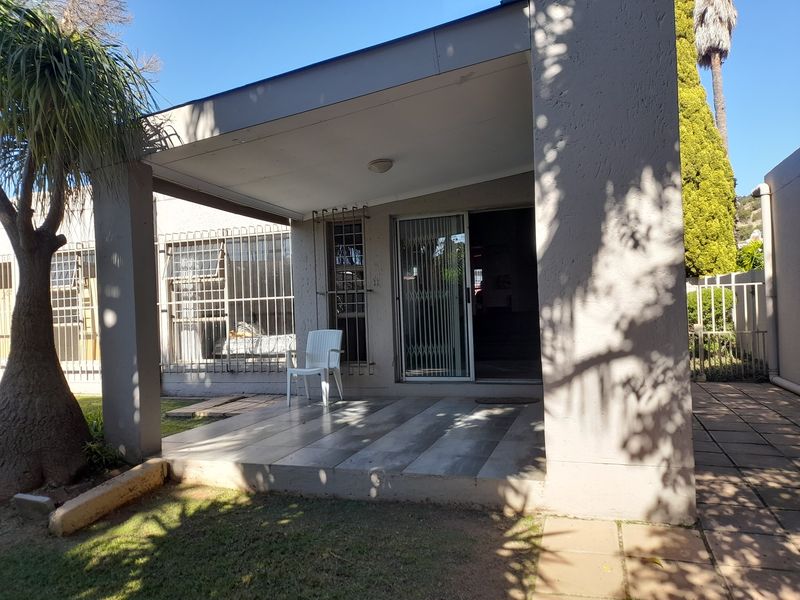 A covered patio area featuring tiled flooring, security gates, and security bars on the windows, providing a functional outdoor space.