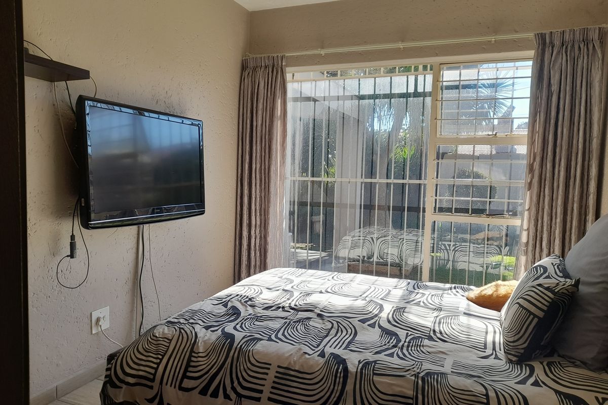 A bedroom featuring tiled flooring, security bars on the sliding door, and curtain rails, providing direct access to the outdoor area.