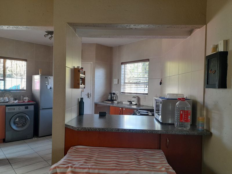 A functional kitchen featuring built-in cabinetry, granite countertops, and tiled backsplash, with an open-plan layout connecting to the adjacent utility area.