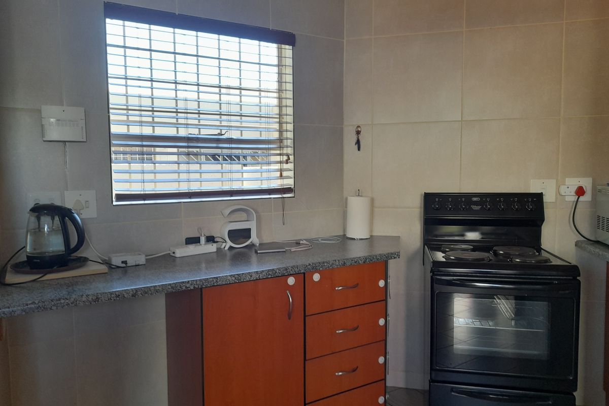 A functional kitchen area featuring tiled walls, laminate countertops, built-in cabinetry, and a freestanding electric stove.