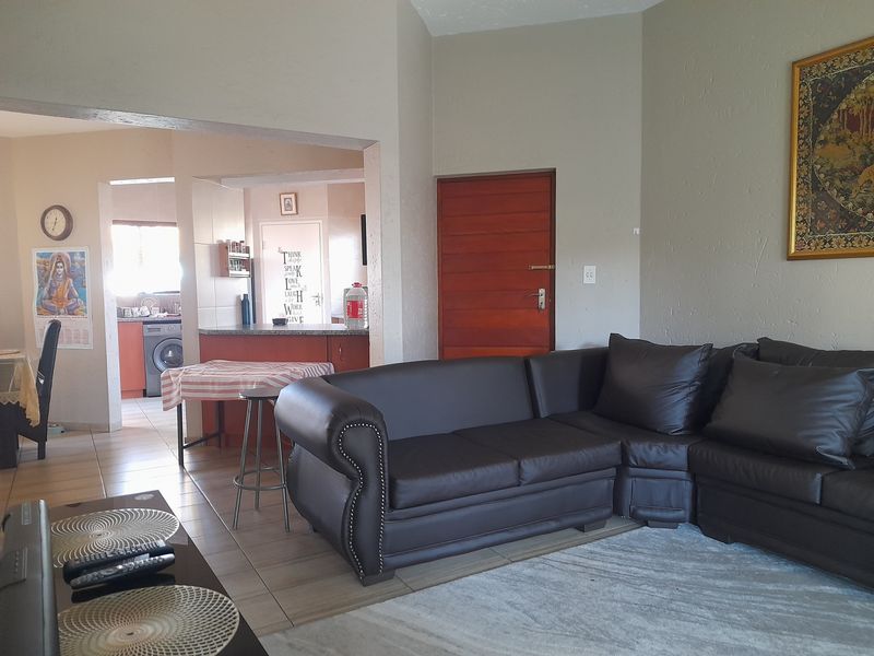 Open-plan living area featuring tiled floors and a connected kitchen space with built-in cabinetry and counter area.