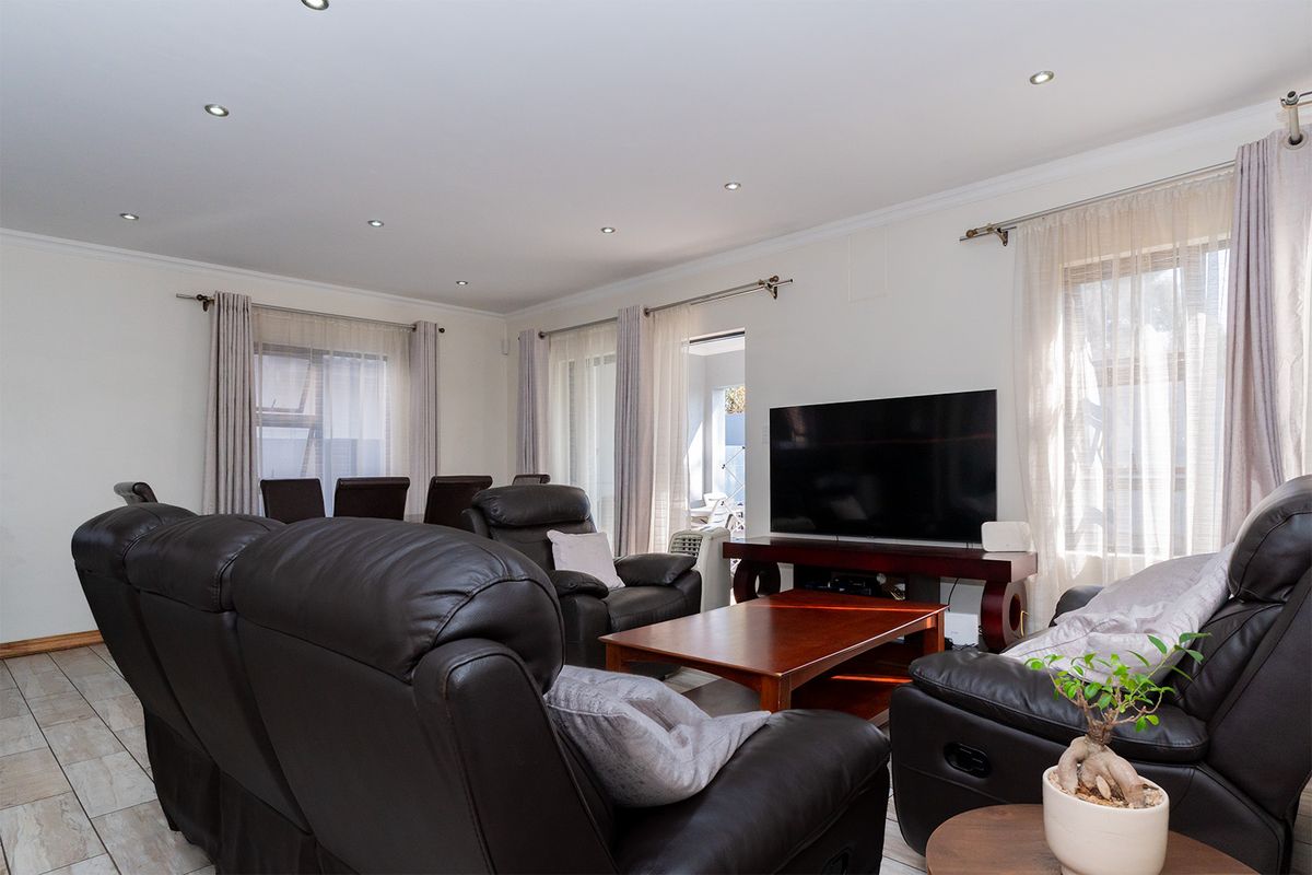 A well-lit living room featuring tiled flooring and recessed downlights, offering a comfortable and functional space for relaxation.