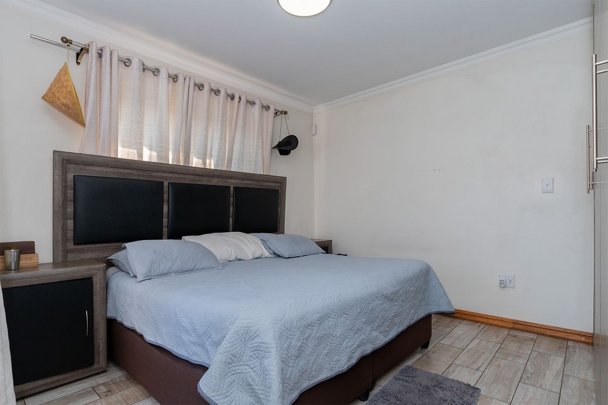 A functional bedroom featuring tiled flooring, built-in cupboards, and neutral wall finishes, providing a comfortable and practical living space.