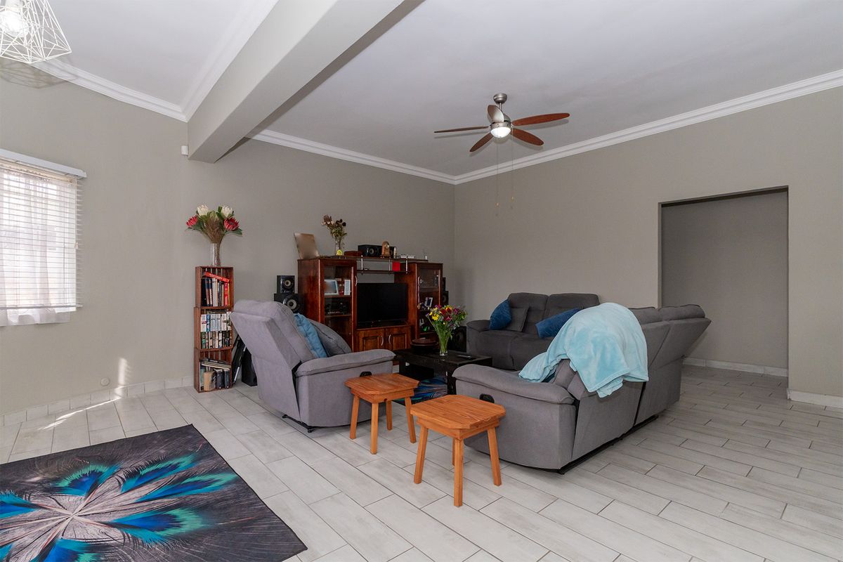 Spacious living room featuring neutral wall tones, tiled flooring, and a ceiling fan, providing a comfortable and functional area for relaxation.