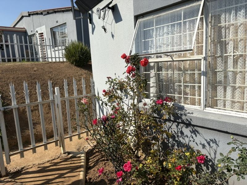 Exterior view of the property rear featuring security bars on windows and metal perimeter fencing.
