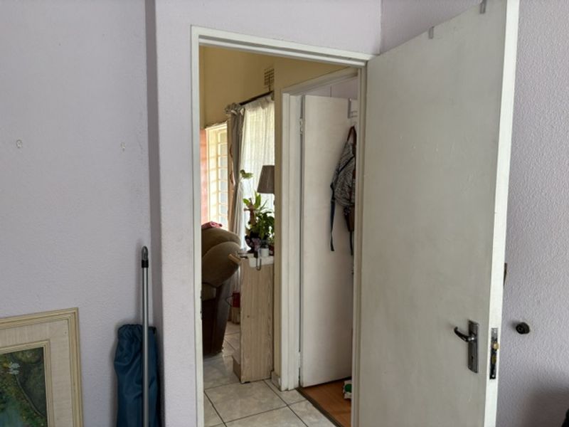 A view through a doorway into a connecting hallway area with tiled flooring and access to adjacent rooms.