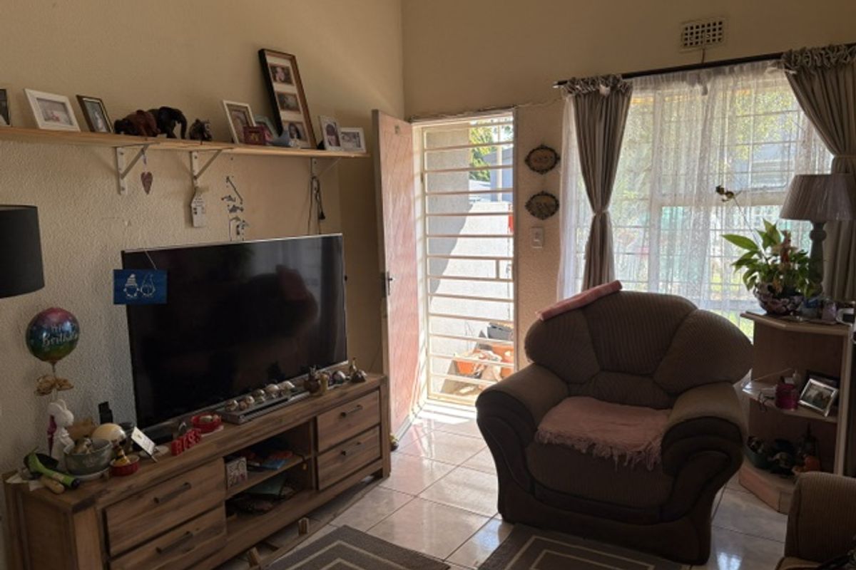 A living room area featuring tiled flooring, a security gate at the entrance, and wall-mounted shelving.