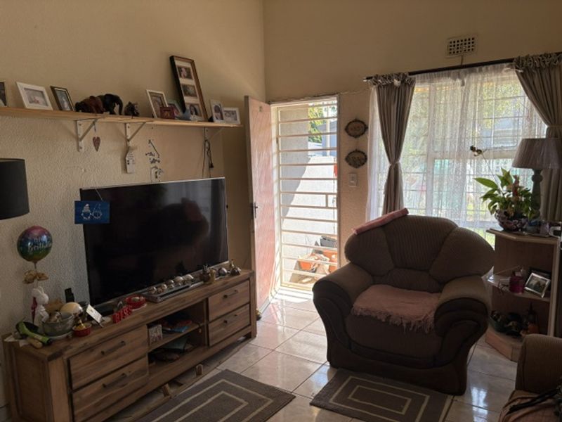 A living room area featuring tiled flooring, a security gate at the entrance, and wall-mounted shelving.