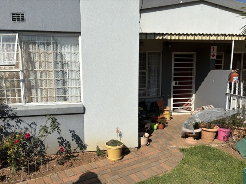 Front exterior view of the apartment featuring a paved walkway, security gates, and security bars on the windows.