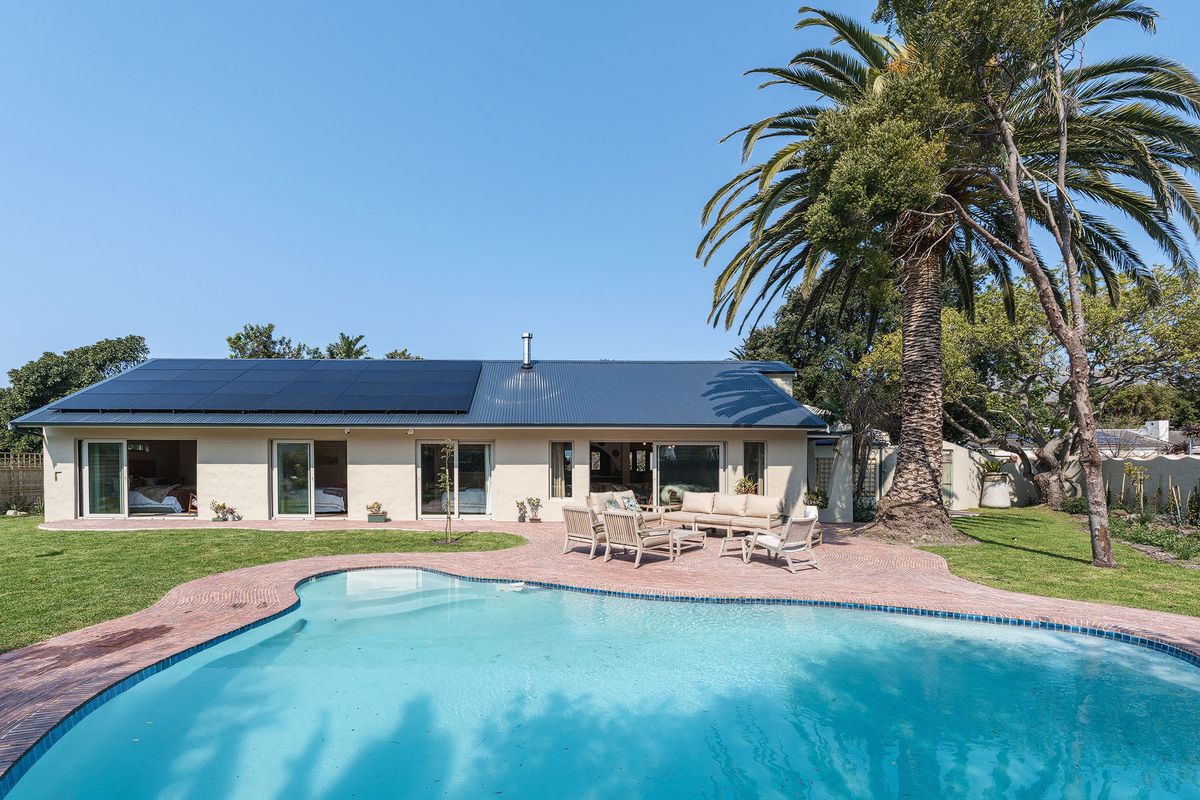 Rear view of the property featuring a swimming pool, paved patio area, and a roof equipped with solar panels.