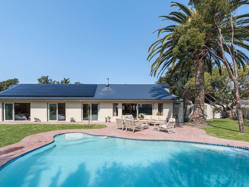 Rear view of the property featuring a swimming pool, paved patio area, and a roof equipped with solar panels.