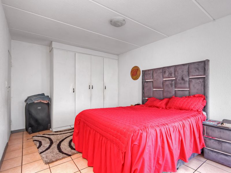 A bedroom featuring tiled flooring and built-in cupboards, requiring cosmetic updates to improve the overall aesthetic and finish.