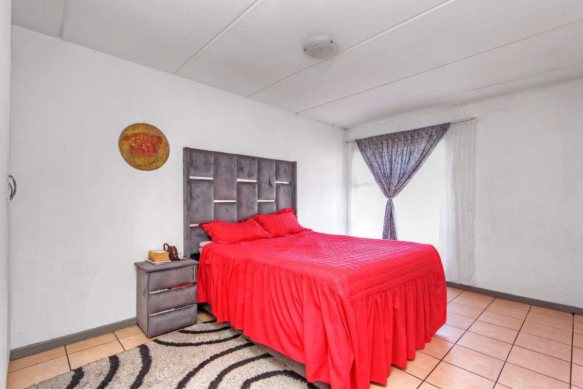 A bedroom featuring tiled flooring and a standard ceiling light fixture, requiring cosmetic updates to improve the overall finish and appeal.