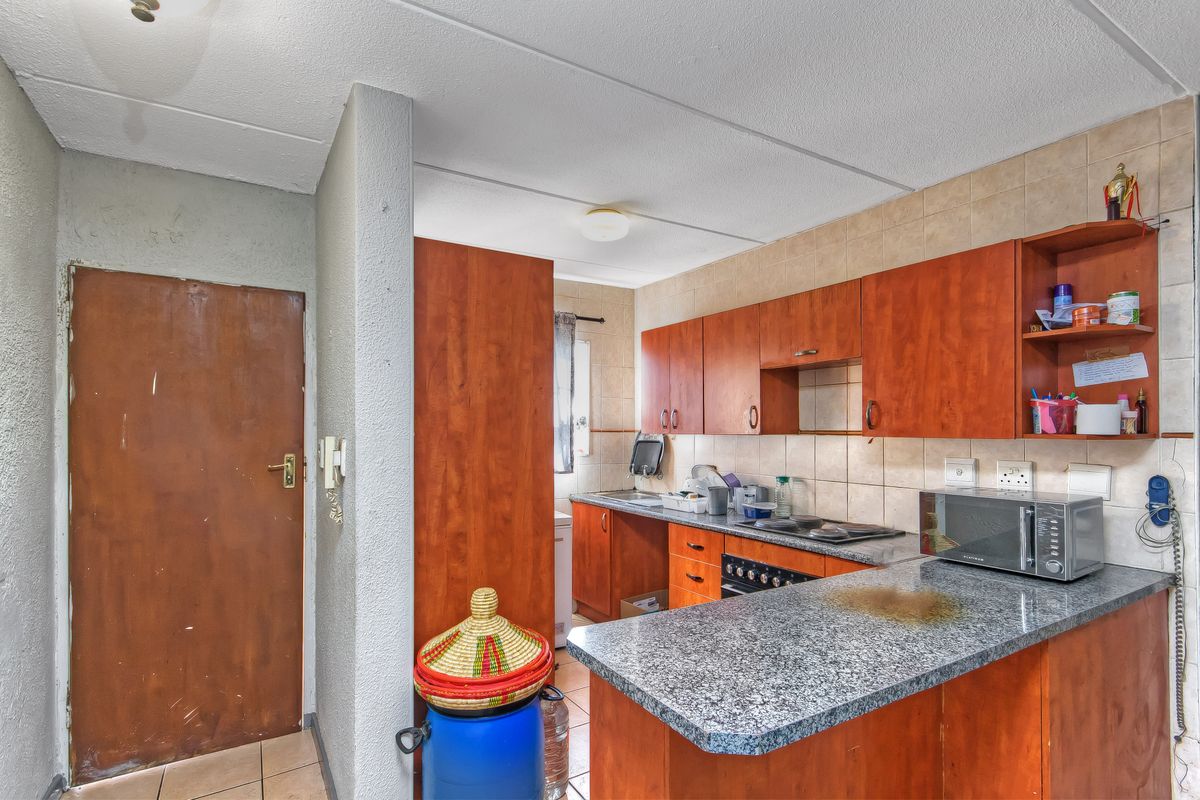 A functional kitchen featuring wood-finish cabinetry, granite countertops, and a built-in oven, offering a practical layout with potential for cosmetic updates.