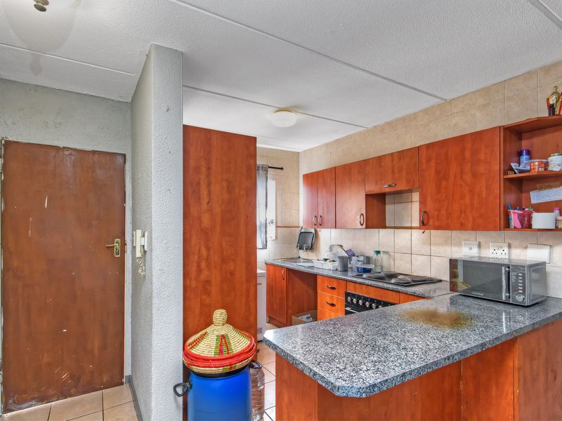 A functional kitchen featuring wood-finish cabinetry, granite countertops, and a built-in oven, offering a practical layout with potential for cosmetic updates.