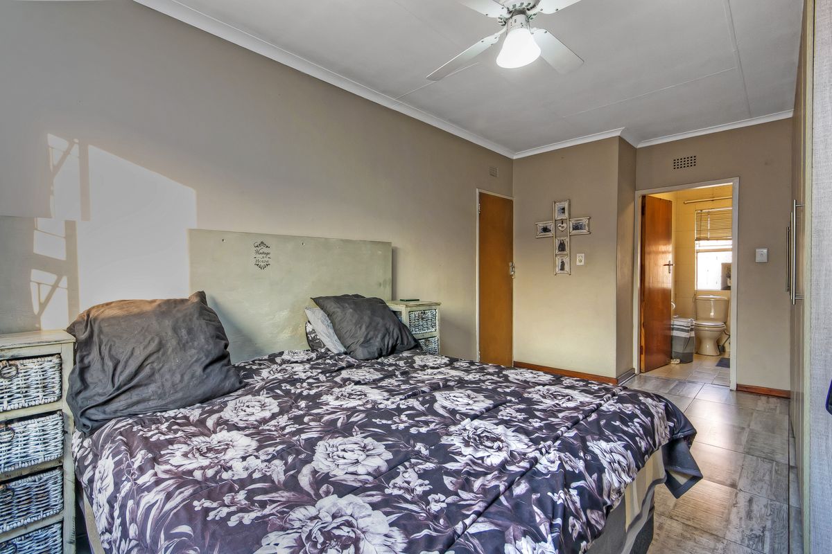 A bedroom featuring tiled flooring, a ceiling fan, and an en-suite bathroom access point.