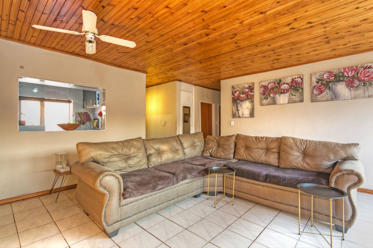 Living room featuring a timber-clad ceiling, tiled flooring, and a service window opening into the kitchen area.