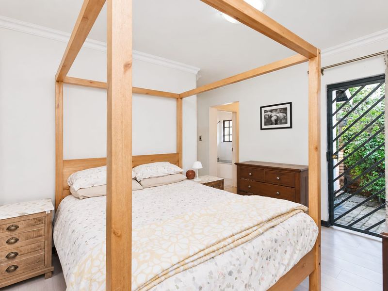 A well-lit bedroom featuring tiled flooring, crown molding, and direct access to an outdoor area through a secure metal gate.
