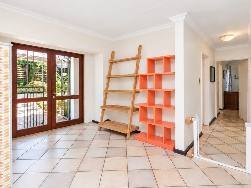 Bright entrance hall featuring tiled flooring and double glass doors leading to the outdoor area, providing a welcoming transition into the home.
