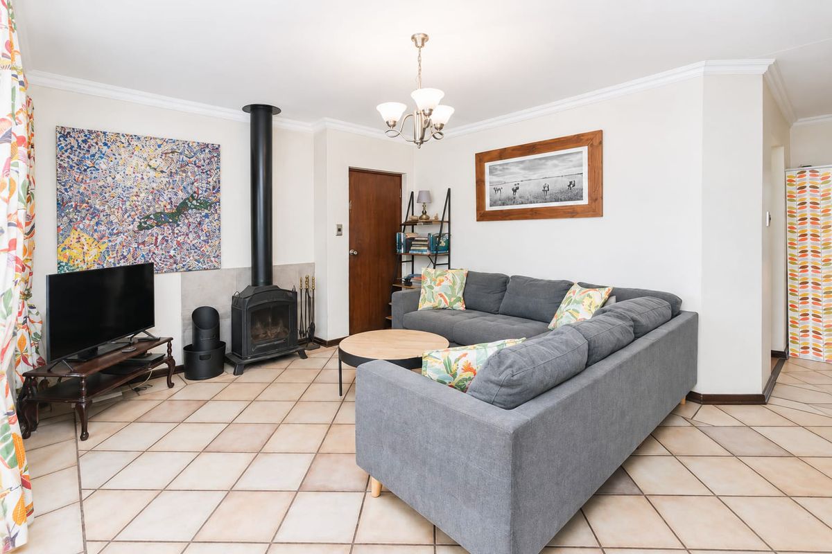 A comfortable living room featuring a freestanding fireplace, ceramic tile flooring, and classic crown molding, creating a warm and inviting atmosphere.