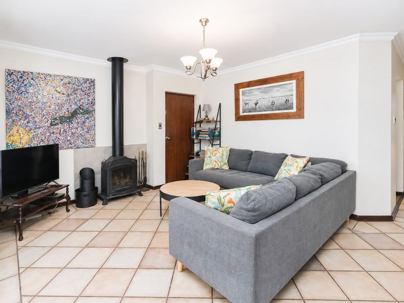 A comfortable living room featuring a freestanding fireplace, ceramic tile flooring, and classic crown molding, creating a warm and inviting atmosphere.