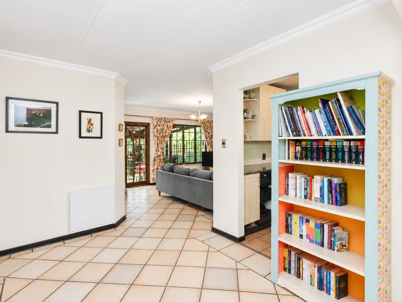 Open plan living area featuring ceramic tiled flooring, crown molding, and a view through to the adjacent kitchen and living space.